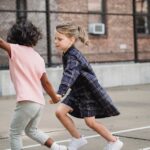 Two smiling girls holding hands and playing on a playground, showcasing friendship and diversity.