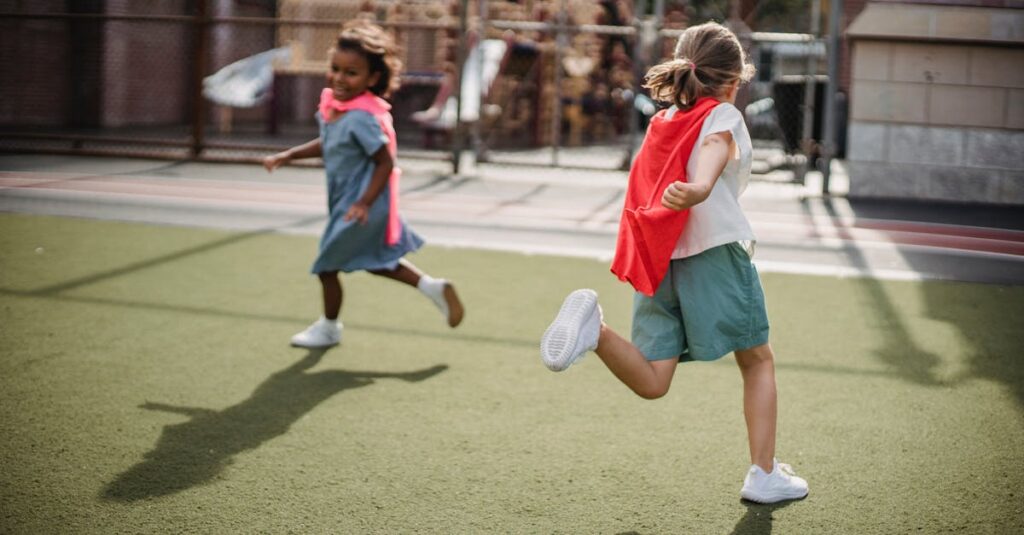 Two children enjoying playtime with capes on an outdoor playground, running on a sunny day.
