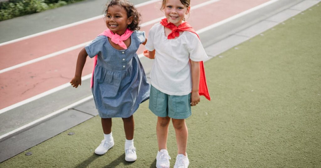 Two young girls wearing capes share a joyful moment on a school playground.