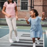 Two young girls happily playing hopscotch on a sunny day in the park.