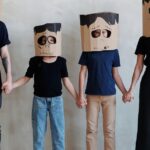 Family dressed in DIY cardboard costumes, holding hands for Halloween fun.
