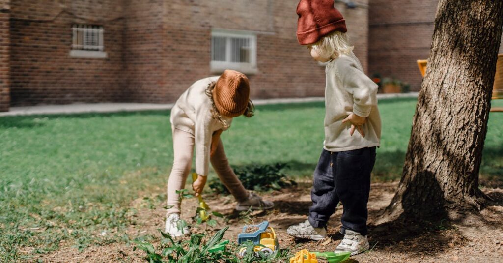 Unrecognizable little kids in casual outfits and brown hats playing with toys on backyard beside big tree