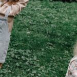 Two kids enjoying playful activities in a lush green yard during the day.