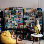 A mother and children enjoy reading in a colorful library section with diverse book selections.