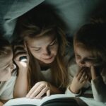 Mother reading a book to her children under a cozy blanket tent, bonding time.