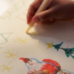 A child drawing a Christmas card, illustrating Santa and festive symbols.