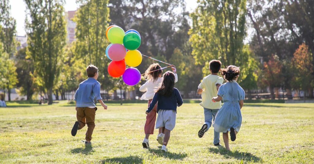 Children happily running with balloons in a sunny park, capturing friendship and joy.