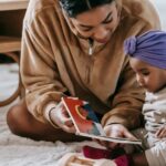 A mother and her baby bonding over a book on the floor of a cozy living room.