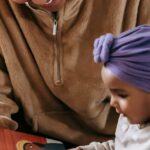A mother and her baby enjoying a bonding moment while reading indoors.