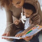 A mother and her child bonding over a book in a cozy indoor setting.