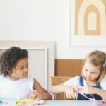 Two children happily crafting at a table filled with colorful art supplies, fostering creativity.