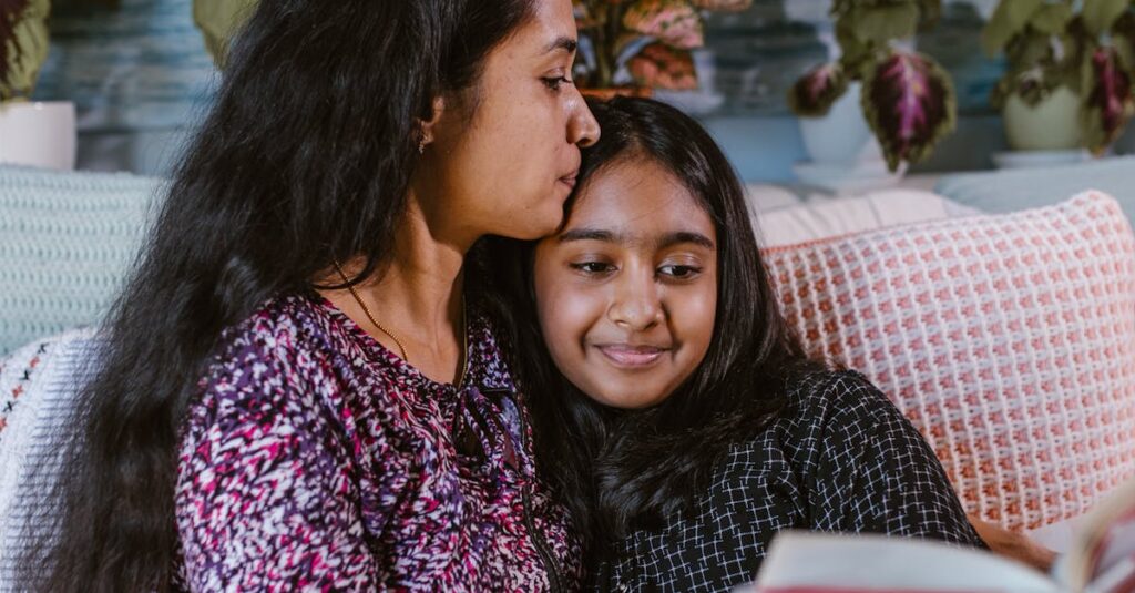 A loving mother and daughter share a bonding moment while reading a book indoors.