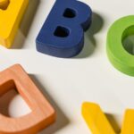 Bright and colorful wooden alphabet letters scattered on a white surface.