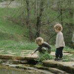 Three children exploring a pond in a lush, green setting during spring. A serene outdoor adventure.