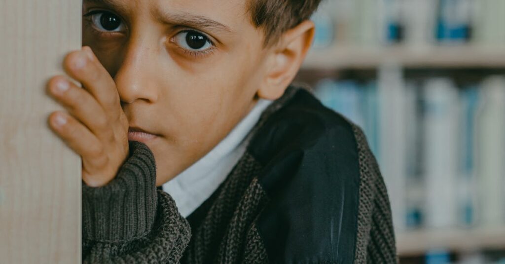 A young Middle Eastern boy looks concerned while standing in a library, showcasing emotions.