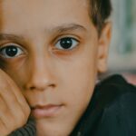 Close-up portrait of a child with expressive eyes, conveying deep emotion indoors.