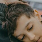 A child peacefully sleeping on a desk in a classroom with blurred background.