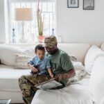 A father and son enjoy bonding time together, reading in a cozy living room.