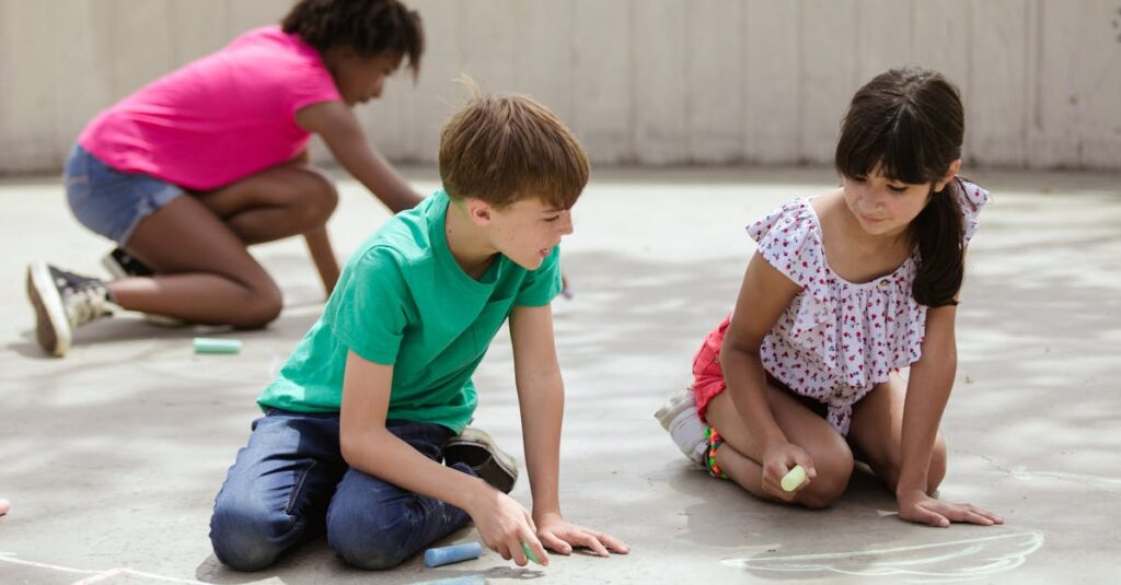 Kids enjoying outdoor activities by drawing with chalk on a concrete surface during summer.