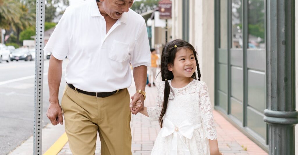 Elderly man and young girl holding hands and smiling while walking outdoors.