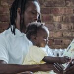 A father and child bonding while reading a book together at home, creating a warm family moment.