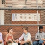 A group of teenagers studying collaboratively on an outdoor sports ground.