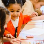 Joyful children drawing and learning in a bright, lively classroom setting.