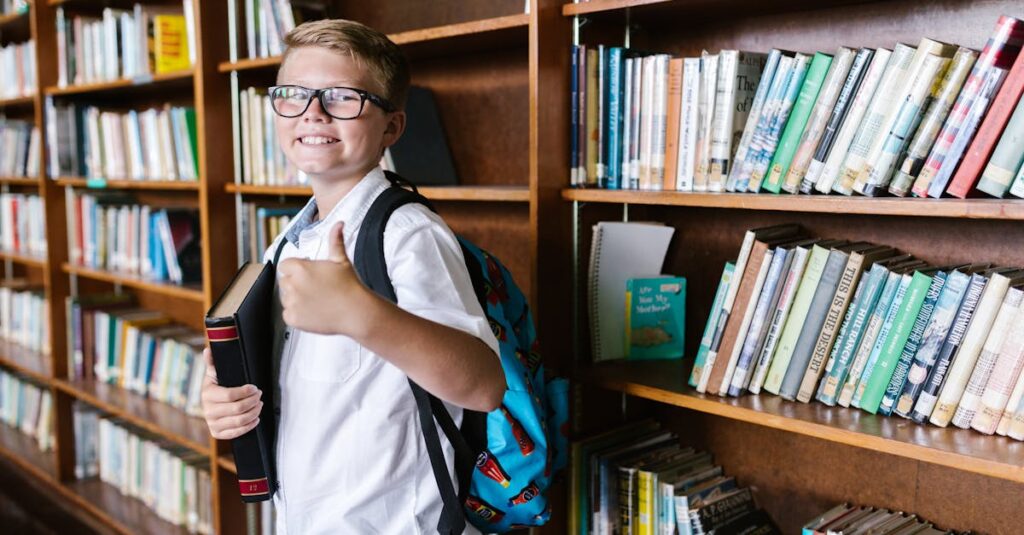 Young boy in a library gives a thumbs up while holding a book. Perfect for back-to-school themes.