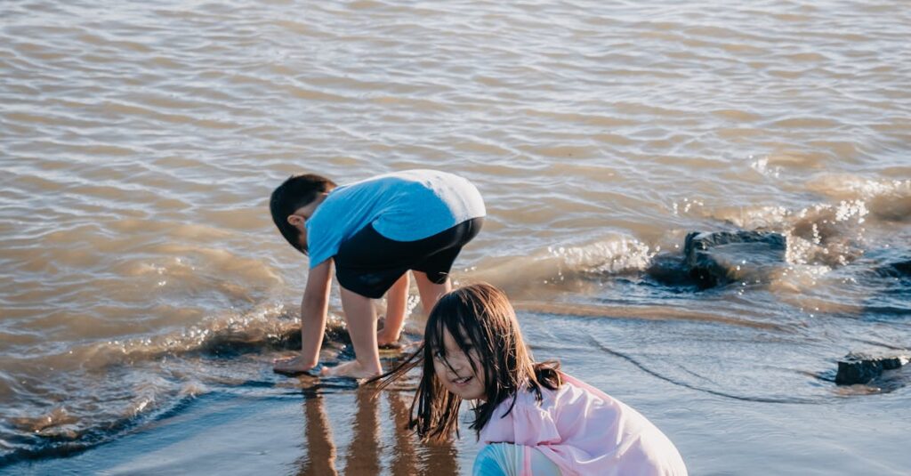 Kids play barefoot on a sunny beach, enjoying the water and sand.