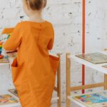 A young girl plays with educational toys in a colorful preschool classroom setting.