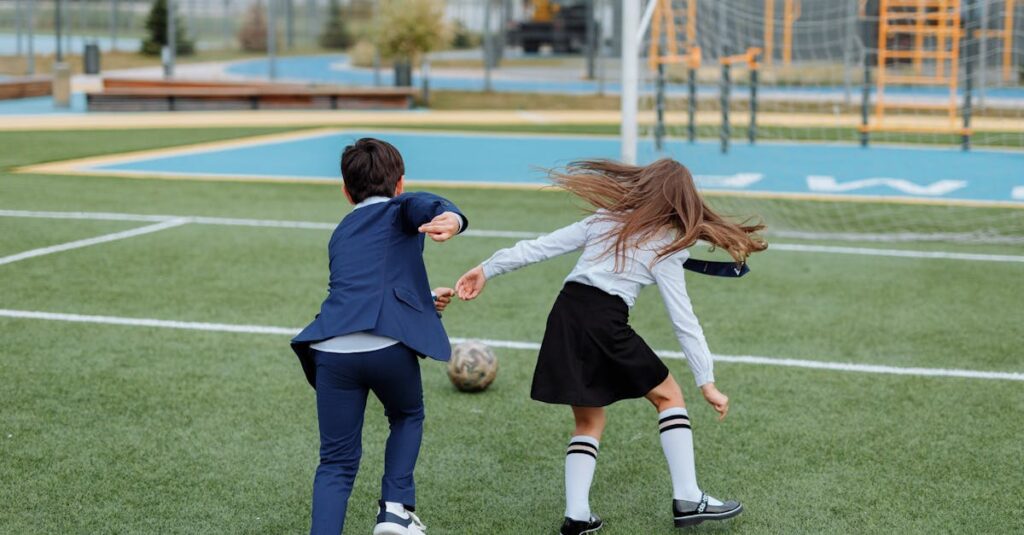 Two children in school uniforms playing soccer on a field, enjoying outdoor fun.
