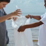 Two children picking up plastic trash on a sandy beach.