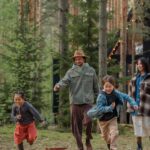 Happy family playing and running through the forest, enjoying a vacation together.