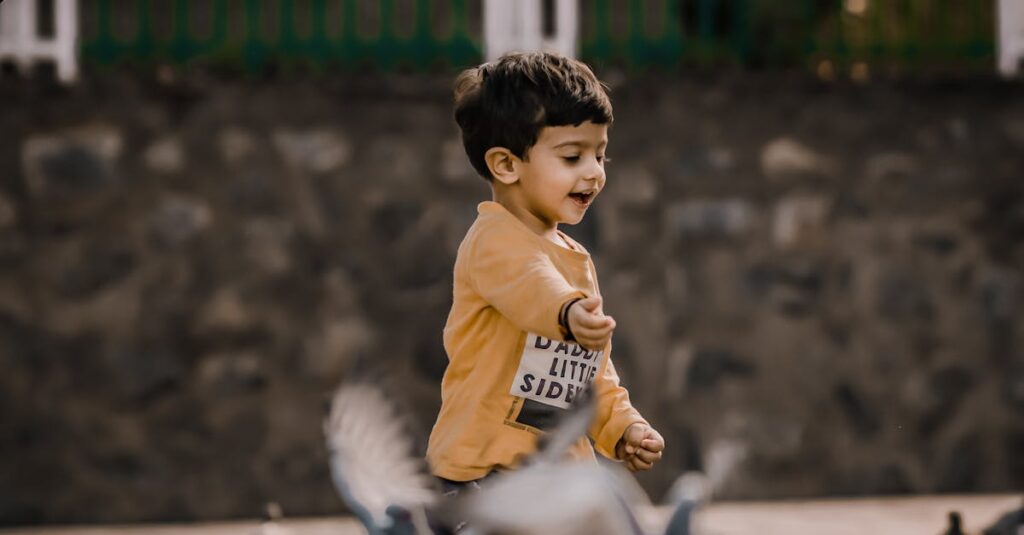 A young boy joyfully playing among pigeons in an outdoor setting, capturing pure childhood happiness.