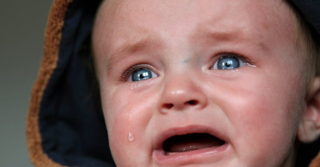 Emotional close-up of a baby in tears, highlighting raw emotion and vulnerability.