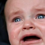 Emotional close-up of a baby in tears, highlighting raw emotion and vulnerability.