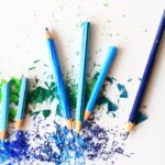 Creative display of colored pencils and vibrant shavings on a white background.