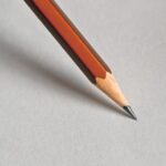 Detailed close-up of a wooden pencil resting on white paper, perfect for educational themes.