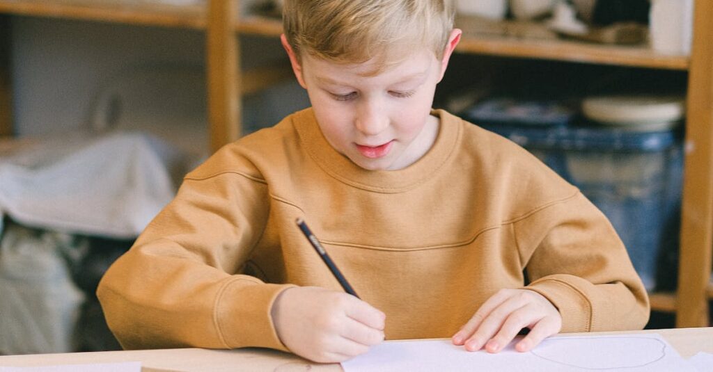 A young boy writing at a table in an art studio with a sign reading 'THERE'S NO PLANET B'.