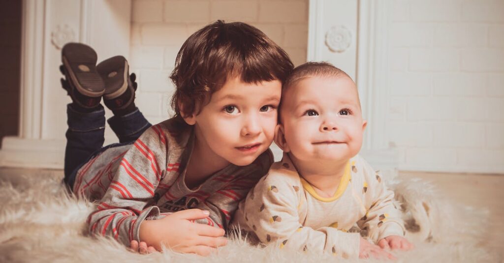 Two young siblings lying on a fluffy rug indoors, exemplifying warmth and family bonding.