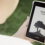 A child holds a Kindle device outdoors, highlighting the ease of reading with technology.