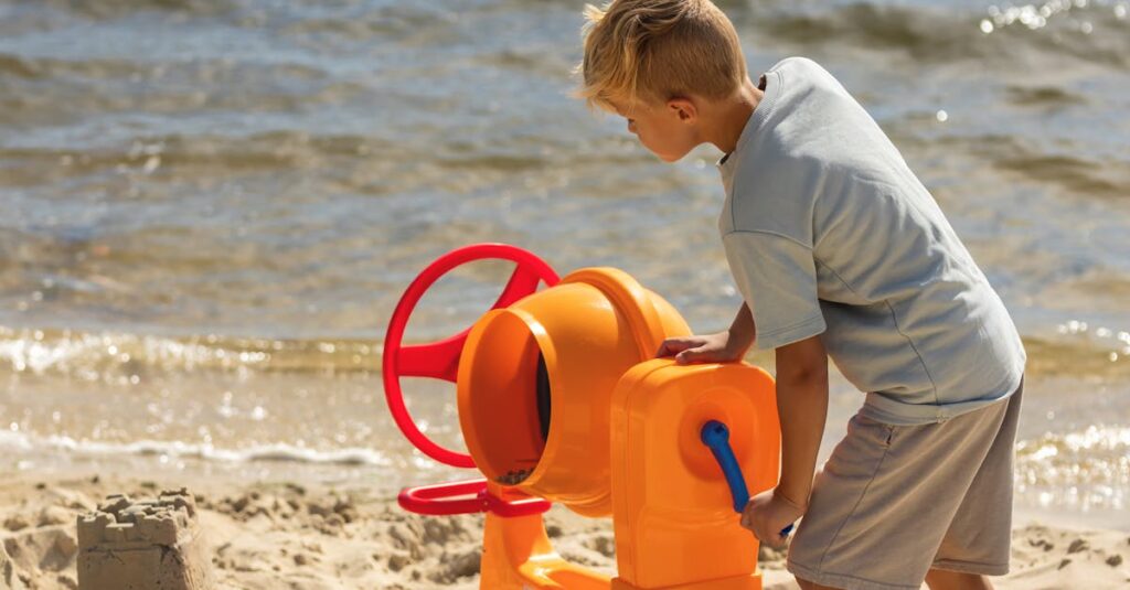 Boy enjoys active play with a toy cement mixer on a sunny lakeside beach in summer.