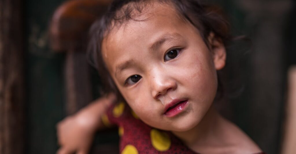 Charming portrait of a child with expressive eyes in a polka-dotted dress indoors.