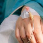Close-up of a patient's hand with intravenous therapy and pulse oximeter, symbolizing healthcare and treatment.