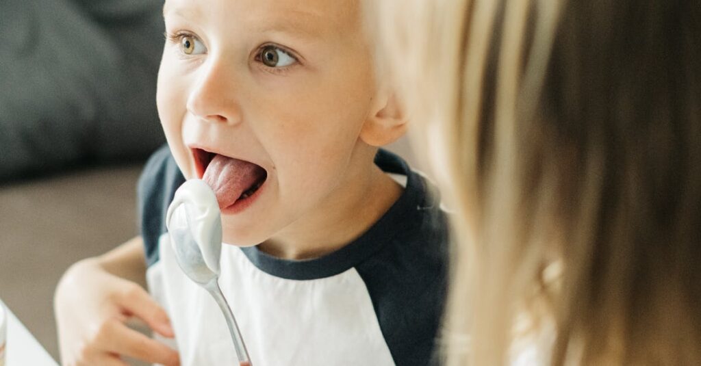 Two playful siblings enjoying a moment together while sharing ice cream indoors.