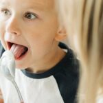 Two playful siblings enjoying a moment together while sharing ice cream indoors.