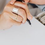 Close-up of a parent and child writing on paper together indoors, showcasing bonding and creativity.