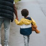 A father and son enjoying a walk in the city, holding hands on a rainy day.