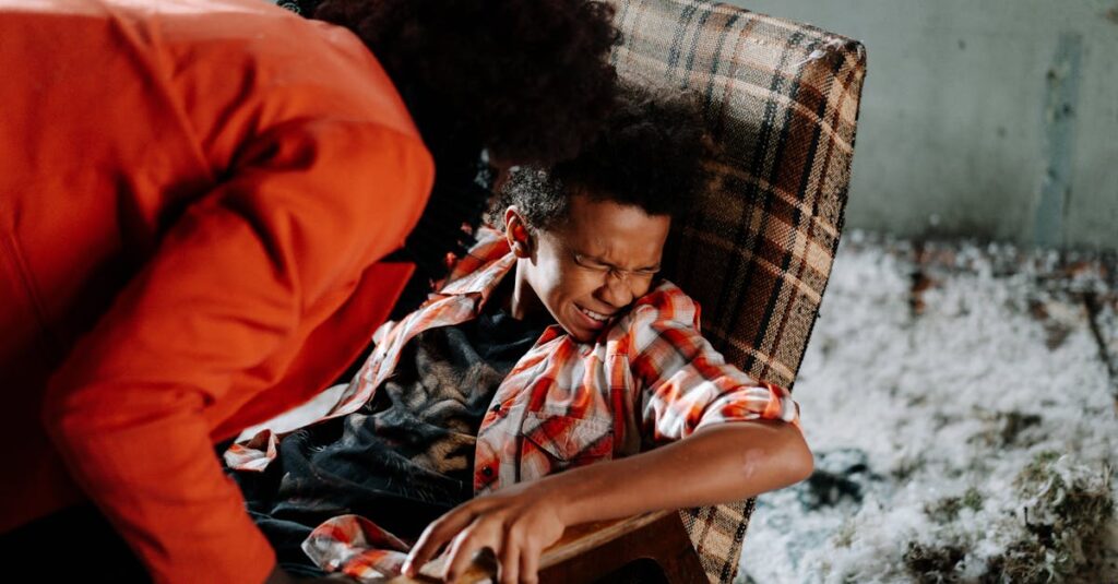 Child in distress on checkered chair with adult leaning over ominously inside a dimly lit room.