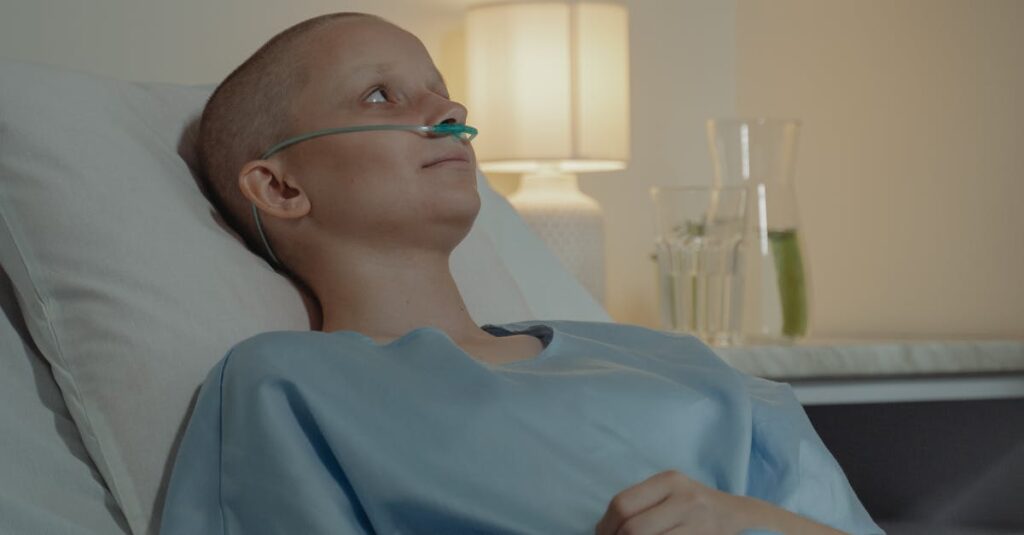 Bald woman in hospital bed receiving oxygen support, showing resilience in illness.